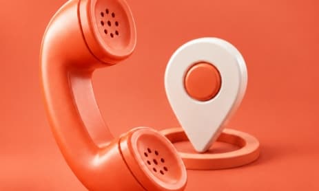 An orange telephone handset beside a location pin
